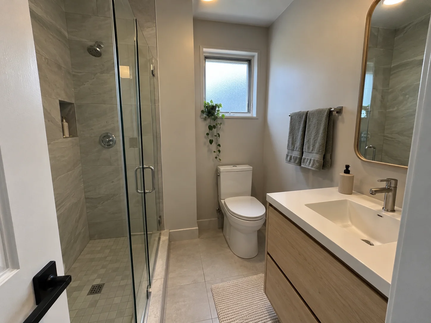 A compact bathroom with a glass shower and oak vanity